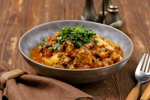 A flavorful vegetable curry fills a rustic bowl, garnished with fresh herbs. The dish is presented on a wooden table, creating a warm, inviting atmosphere perfect for a meal.