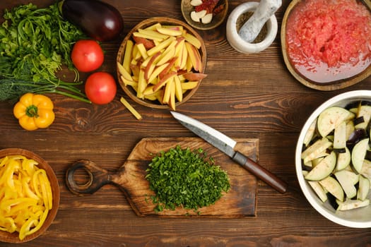 A vibrant assortment of fresh vegetables and herbs is spread across a wooden table. Herbs, tomatoes, and bell peppers are ready for chopping, showcasing the preparation for a nutritious dish.