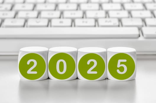 Letter dice in front of a keyboard - 2025