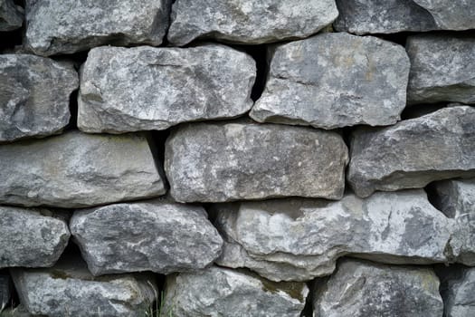 A sturdy wall built from large gray stones is displayed in natural light showcasing its rugged texture and arrangement.