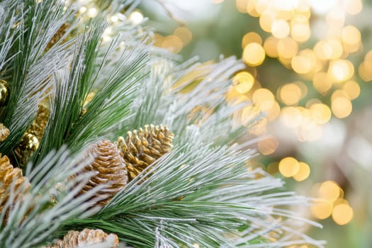 Frosted pine branches adorned with golden pinecones and soft glowing lights create a warm festive atmosphere during winter.