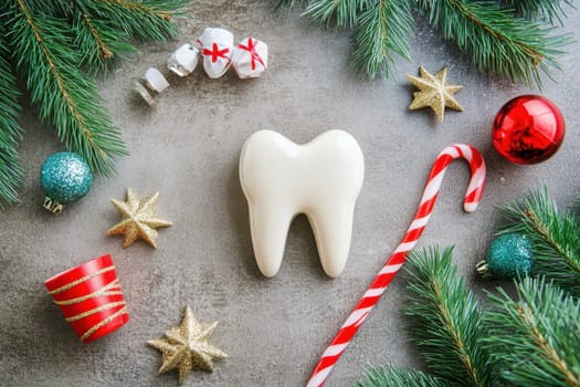 A festive arrangement features a white tooth surrounded by ornaments candy canes and pine branches capturing a playful holiday spirit.