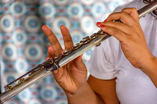 Detail of the hands of a woman playing the transverse flute during a musical performance