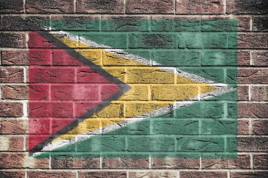 A Guyana flag painted on brick wall background red yellow green star black