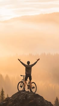 A cyclist stands triumphantly on a hill with arms raised, celebrating the sunrise in a breathtaking landscape.