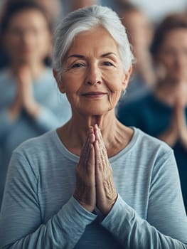 Senior woman in a group setting practicing mindfulness with hands in a prayer position.