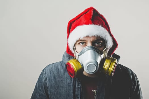 A man is donning a Santa hat atop a gas mask combining festive and unusual elements for a unique holiday celebration.