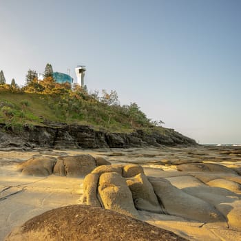 Point Cartwright Headland late afternoon as sun sets in the west , lighthouse, water tank , cliff face and rocky platform