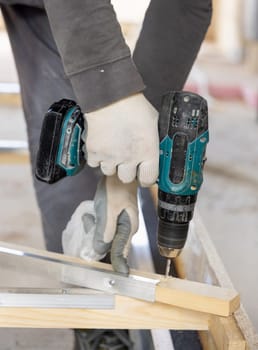 Carpenter working on wooden board to produce construction material or wooden furniture. Craftman using professional electric cordless drill. DIY concept