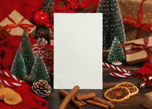 Greeting card near Christmas decor, trees, spices and red knitted sweater on dark wooden table closeup, place for text. Winter atmospheric mock up, family holiday time