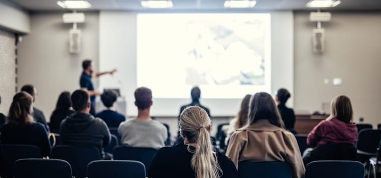 Speaker giving a talk in conference hall at business event. Rear view of unrecognizable people in audience at the conference hall. Business and entrepreneurship concept