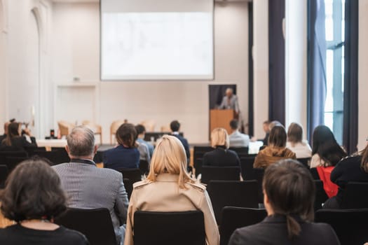 Speaker giving a talk in conference hall at business event. Rear view of unrecognizable people in audience at the conference hall. Business and entrepreneurship concept