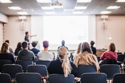 Speaker giving a talk in conference hall at business event. Rear view of unrecognizable people in audience at the conference hall. Business and entrepreneurship concept