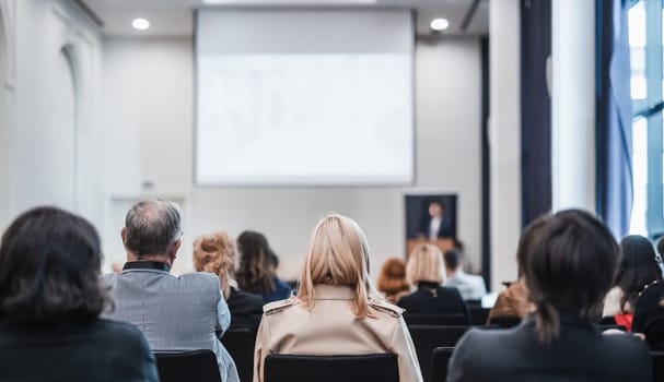 Speaker giving a talk in conference hall at business event. Rear view of unrecognizable people in audience at the conference hall. Business and entrepreneurship concept