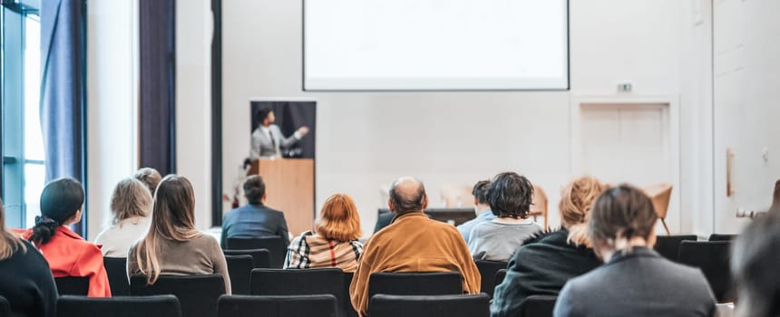 Speaker giving a talk in conference hall at business event. Rear view of unrecognizable people in audience at the conference hall. Business and entrepreneurship concept