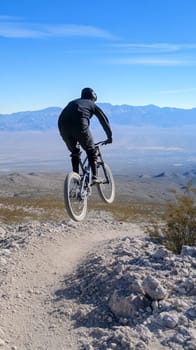 A mountain biker navigates a rocky trail against a backdrop of vast desert landscapes and blue skies.