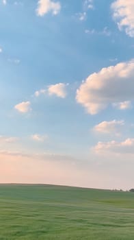 Expansive sky with soft, puffy clouds over a green field, evoking a sense of freedom and openness.