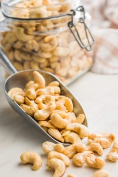 Roasted cashew nuts in scoop on a kitchen table.
