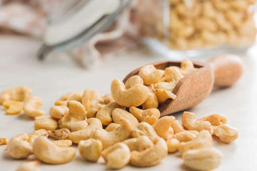 Roasted cashew nuts in scoop on a kitchen table.