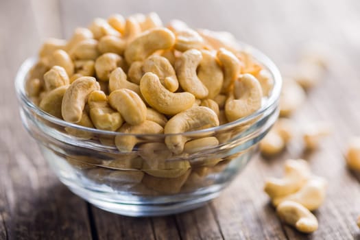 Roasted cashew nuts in bowl on a wooden table.