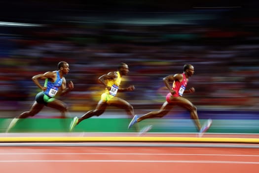 Three athletes sprinting on an olympic track, showcasing speed and competition with dynamic blurred motion