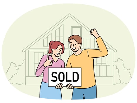 Happy couple is standing near house with inscription sold, rejoicing in sale of real estate at bargain price. Satisfied man and woman rejoice in profitable real estate deal and make victory gestures