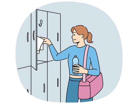 Woman visitor to gym stands near lockers for personal belongings and prepares for sports workout. Girl with bag for sportswear and bottle of water visits gym to maintain good figure