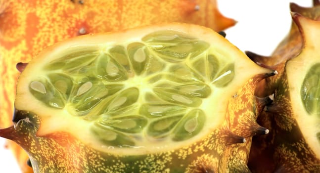 A close-up shot of a horned melon highlighting its vibrant green interior and textured orange exterior, showcasing the fruit's unique and exotic appearance in vivid, fresh colors.