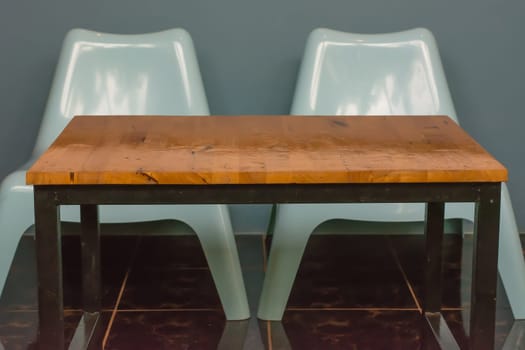 Two white plastic chairs and a wooden table, contrasting the sleek with the rustic.