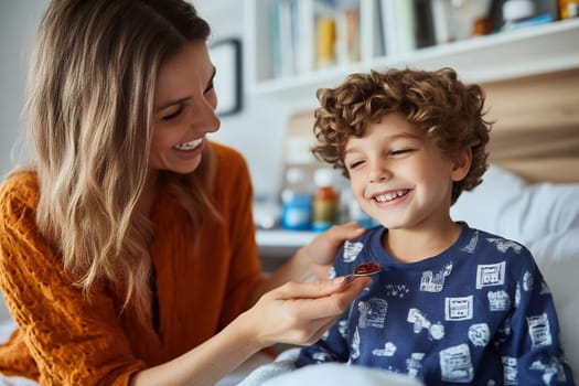 Mother in orange sweater giving medicine to cheerful curly haired child, positive healthcare moment at home with bookshelves background.