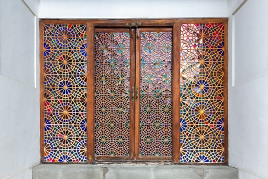 Intricately designed wooden door featuring colorful stained glass leads into Shaki Khans Palace, showcasing traditional Azerbaijani architecture and artistry