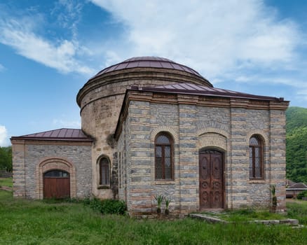The Round Temple, also known as Three Saints Church, located near the Palace of Shaki Khans in Shaki, Azerbaijan, set against a backdrop of a clear blue sky