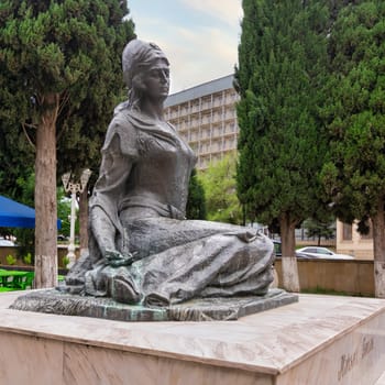 A statue of the esteemed 12th-century Azerbaijani poet Mahsati Ganjavi is elegantly situated, surrounded by verdant trees and outdoor seating in Shaki, Azerbaijan