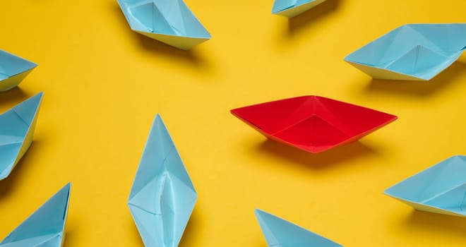 A group of blue paper boats surrounded one red boat, the concept of bullying, search for compromise.