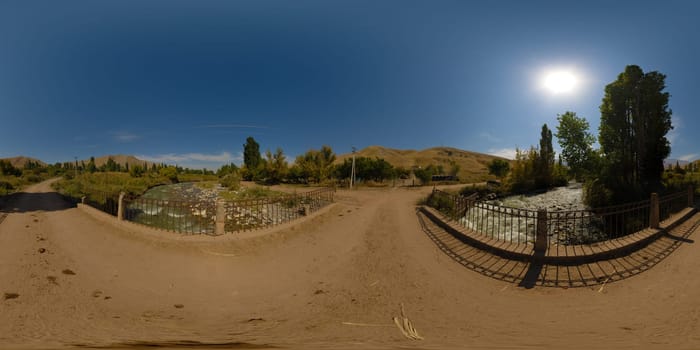Full Spherical panorama of an old dusty bridge over mountain river at sunny autumn day in equirectangular projection. Blue sky with the sun in the sky.