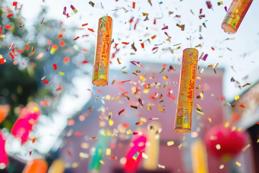 Brightly colored firecrackers hang amidst falling confetti during a lively celebration creating an atmosphere of joy and excitement in the air.