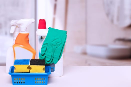 Household cleanliness and hygiene. Close-up of house cleaning products and cleaning supplies on a white table over abstract blurred bath background. Household chore concept. Macro.