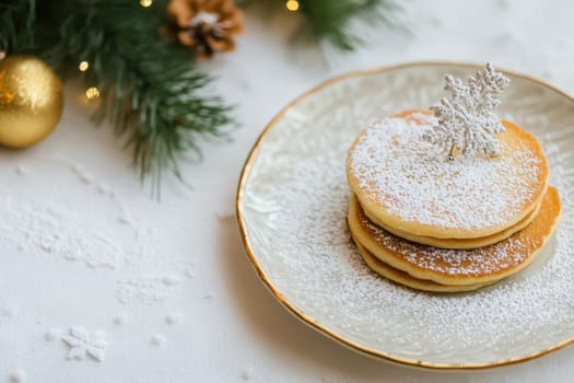 A plate of fluffy pancakes dusted with powdered sugar and adorned with a decorative snowflake set against a holiday backdrop.