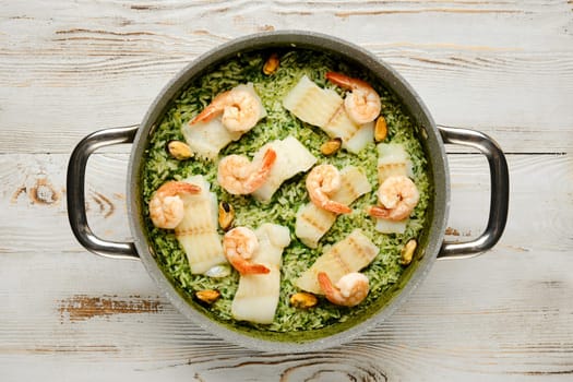 A culinary delight showcases shrimp and fish layered over a vibrant green rice base in a gray casserole. The dish features a medley of flavors, perfect for a family meal or special occasion.