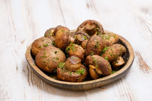 A variety of freshly picked mushrooms is beautifully arranged on a rustic wooden plate, sprinkled with herbs, showcasing their earthy tones.