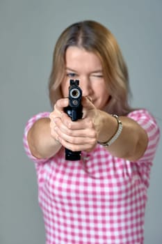 a beautiful woman aims a gun. High quality photo