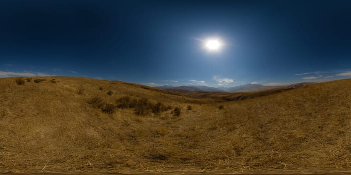 Full Spherical panorama of dry grass foothills at sunny autumn day with clear blue sky above and mountain range on the horizon, equirectangular projection