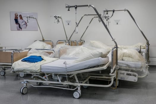 leere Krankenhausbetten stehen mit Folie abgedeckt in einem Krankenhausflur - Symbolbild