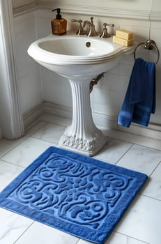 A beautifully designed bathroom features a white pedestal sink, blue rug, and towels, creating a serene and inviting atmosphere.