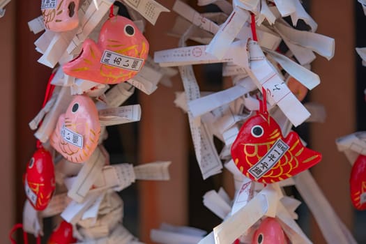 Close up on cute pink and red japanese Aitai mikuji fortune telling papers made in papier-macher shaped as sea bream fish with predicting the love fate in the hikawa shrine of Kawagoe city