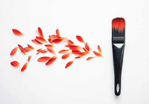 A black brush rests next to scattered red flower petals, showcasing an artistic blend of nature and creativity on a clean surface.