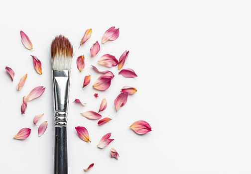 A makeup brush lies in the center, surrounded by scattered pink rose petals, creating an elegant and fresh atmosphere for beauty applications.