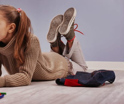 Young girl daydreams on the floor, surrounded by colorful objects, lost in thought and playful
