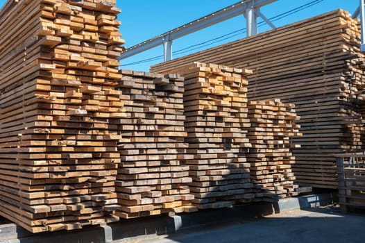 Stacked wooden planks close-up at lumber warehouse. Wood industry concept