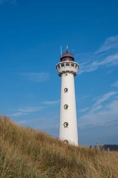 The approx. 28 m high white lighthouse J.C.J. van Speijk in Egmond aan Zee, North Holland, Netherlands, in the sand dunes with beach grass